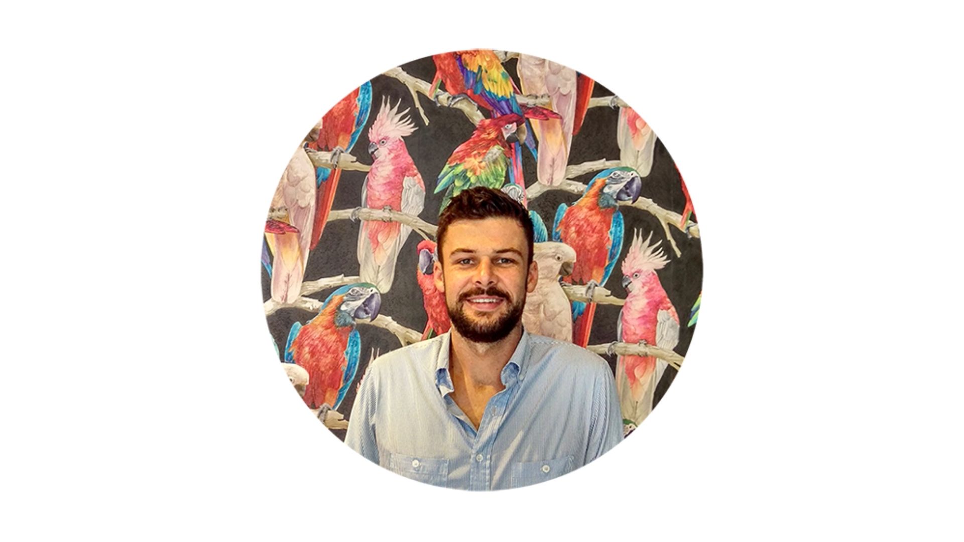 A man in front of a painting of cockatoos and parrots 3