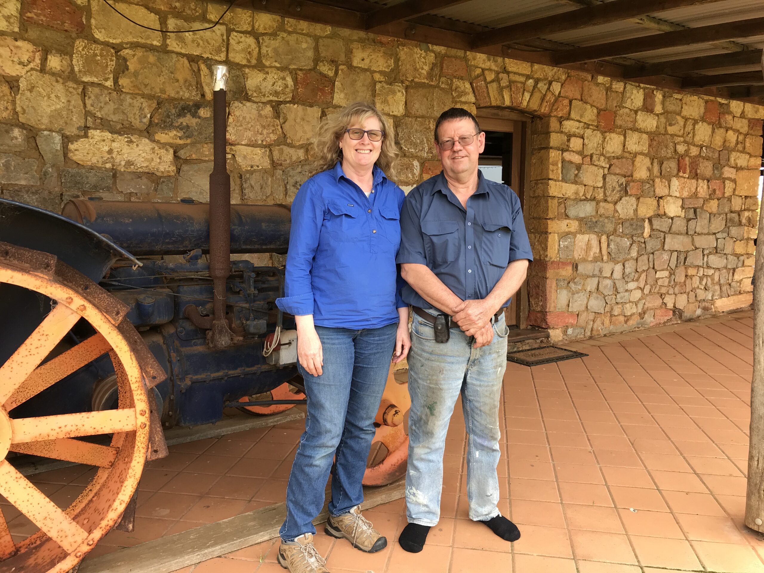 man and woman standing next to each other, background has a steam engine