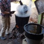 Woman wearing gloves holding pot over a smoking pot