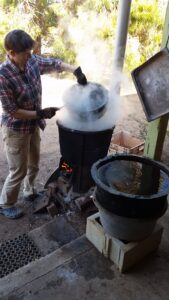 Woman wearing gloves holding pot over a smoking pot