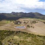 Drone photo of cleared paddock surrounded by remnant bush with ranges in the background