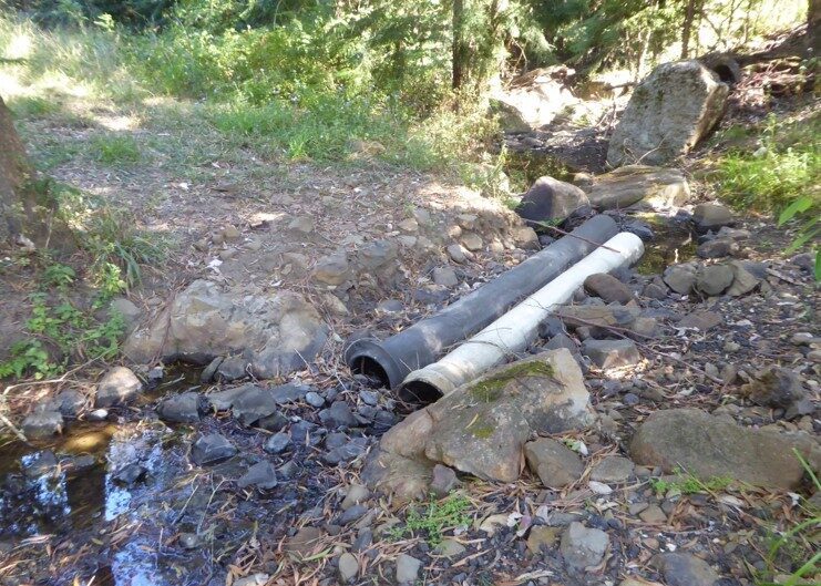 Two cement drain pipes running through a creek crossing