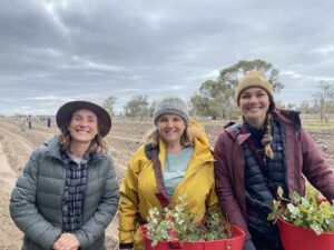 Three women smiling in front of a paddock