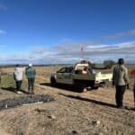 People standing near ute and seedlings looking at the cleared planting area