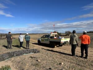 People standing near ute and seedlings looking at the cleared planting area