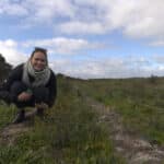 Woman squatting down next to little seedlings growing in planting rows