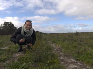 Woman squatting down next to little seedlings growing in planting rows