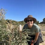 Girl smiling next to a flowering Banksia prionotes ('Acorn banksia').