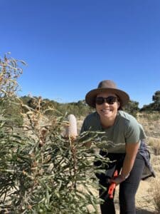 Girl smiling next to a flowering Banksia prionotes ('Acorn banksia').