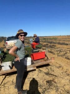 Woman standing and smiling infront of a ute tray full of seedling trays