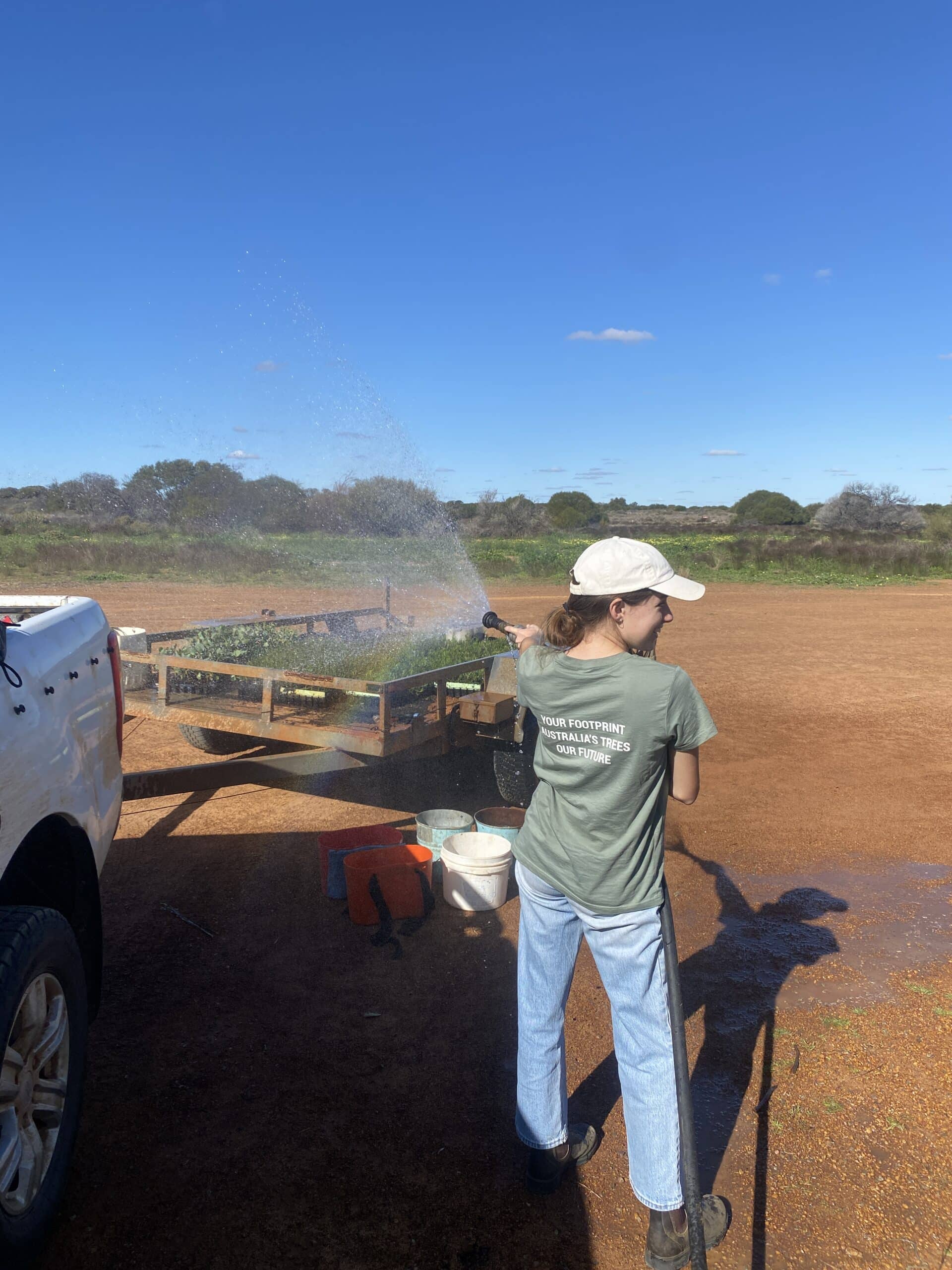 Woman watering seedlings on a trailer