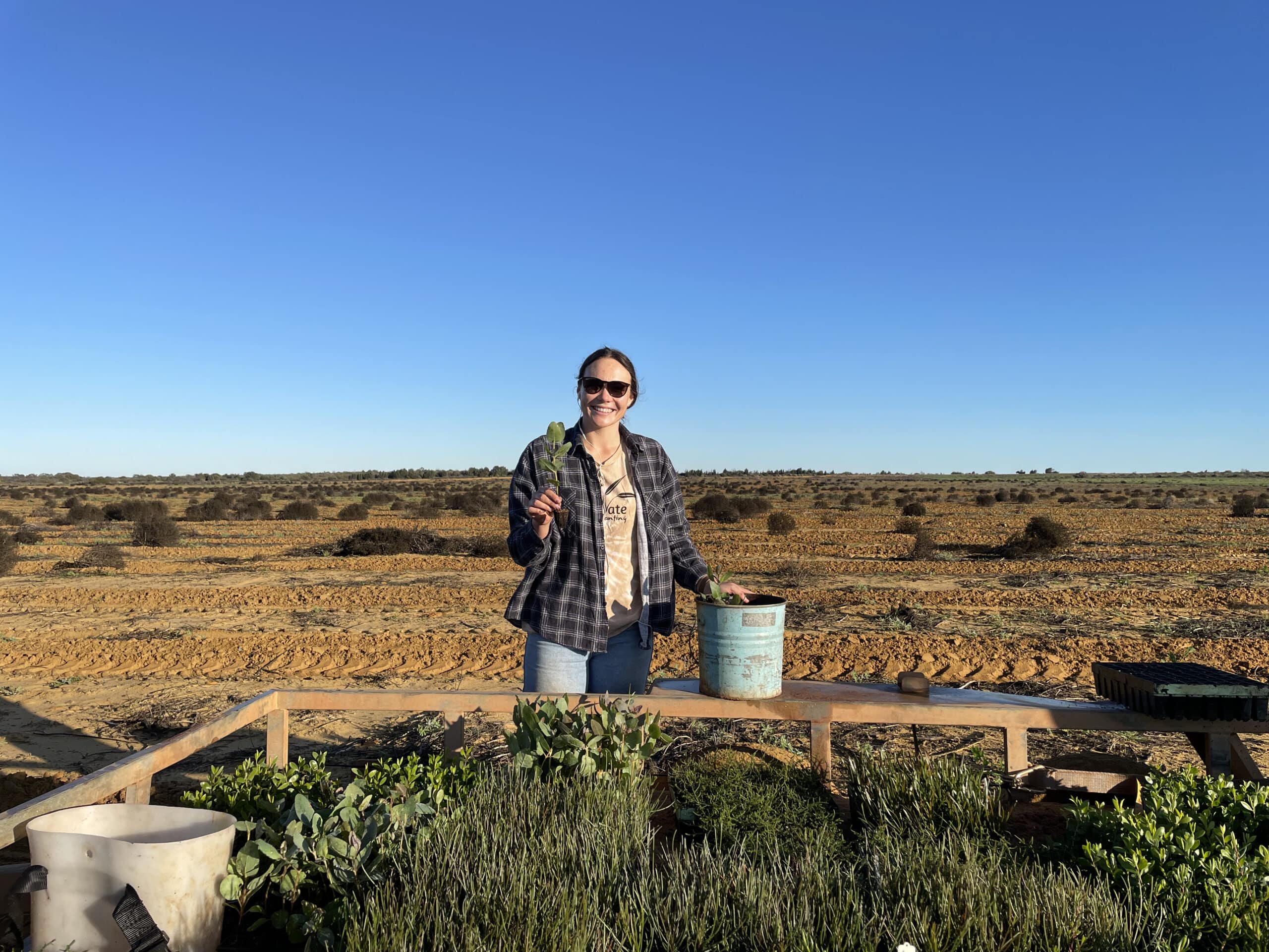 Woman standing behind ute tray full of seedlings