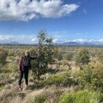 Woman standing next to a Eucalyptus tree with the Stirling Ranges visible in the background.