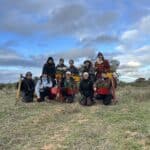 Group photo of ten woman standing and crouching in a field with pottiputki's and seedings buckets