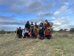 Group photo of ten woman standing and crouching in a field with pottiputki's and seedings buckets