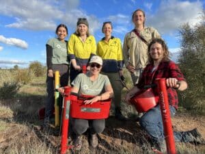 Group photo of 6 people smiling with seedling planters and buckets.