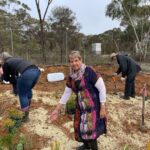 Women standing in foreground with a women and man in background getting ready to plant seedlings.