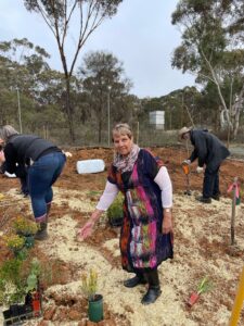 Women standing in foreground with a women and man in background getting ready to plant seedlings.