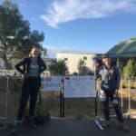 Two women standing next to two signs