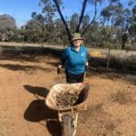 Women moving wheelbarrow full of dirt