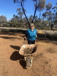 Women moving wheelbarrow full of dirt