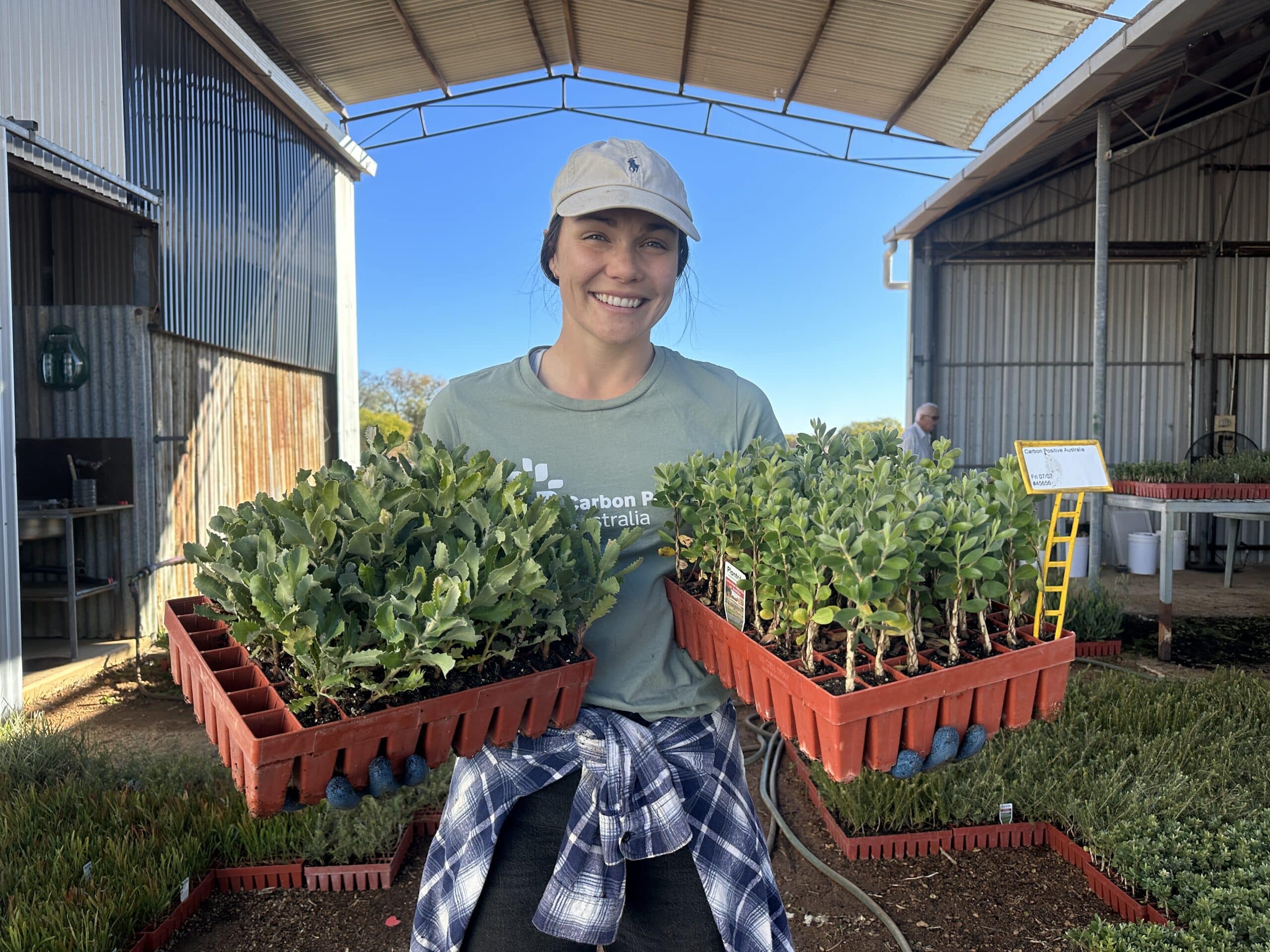 Woman smiling holding a seedling tray in each hand