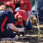 Two female students planting a seedling.