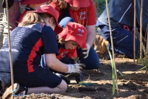 Two female students planting a seedling.