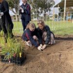 Women helping a child plant a seedling