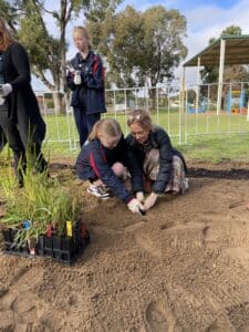 Women helping a child plant a seedling