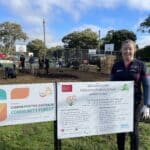 Women standing next to two signs with planting gloves