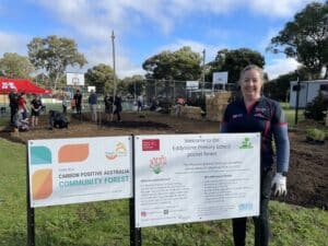 Women standing next to two signs with planting gloves