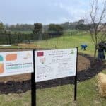 Two signs in front of planting area