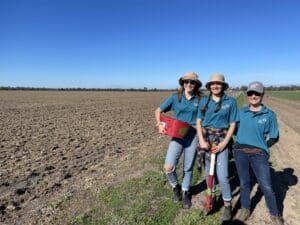 Three women standing and smiling in the middle of a paddock