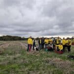 Group photo of people standing together in an empty field with planting rows.