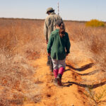 Two people walking alongside a planting row. 