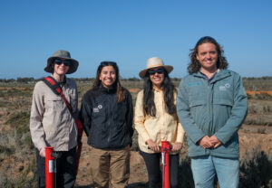 The team standing in front of the planting rows.